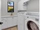 Bright laundry room with white cabinets, washer, dryer, and a utility sink at 14619 Leopard Creek Pl, Lakewood Ranch, FL 34202