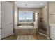 Luxurious primary bathroom featuring a soaking tub, glass-enclosed shower and a chandelier, creating a spa-like retreat at 16215 Tradewind Ter, Lakewood Ranch, FL 34211