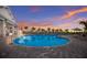 A beautiful blue pool reflects the colors of the sunset, framed by numerous palm trees and lounge chairs at 16215 Tradewind Ter, Lakewood Ranch, FL 34211