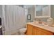 Well-lit bathroom with a wooden vanity, marble countertop, and a shower adorned with a white curtain at 7235 Rangi Dr, Sarasota, FL 34241
