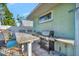 Outdoor kitchen with bar seating and built-in grill, next to a white fence, and lush plants at 7235 Rangi Dr, Sarasota, FL 34241