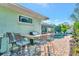 Outdoor kitchen with built-in bar, grill, seating, and backyard pool view on a sunny day at 7235 Rangi Dr, Sarasota, FL 34241