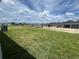 Open backyard with green lawn showing neighborhood homes under a bright sky with puffy clouds at 766 Hillshire Pl, Spring Hill, FL 34609