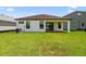 A spacious backyard showcases the house with a covered patio, windows and AC unit surrounded by green grass at 774 Hillshire Pl, Spring Hill, FL 34609