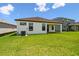Backyard showcasing lush grass, an exterior with black window frames, and an A/C unit at 774 Hillshire Pl, Spring Hill, FL 34609