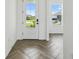 Sun-filled entryway featuring a glass front door and herringbone floors at 774 Hillshire Pl, Spring Hill, FL 34609