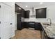 Stylish kitchen featuring dark cabinets, stainless steel appliances, granite countertops and herringbone floors at 774 Hillshire Pl, Spring Hill, FL 34609