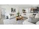 Spacious living room with white sofas, round wooden coffee table, and large windows, virtually staged at 774 Hillshire Pl, Spring Hill, FL 34609