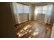 Bright bedroom with lots of natural light, wood floors, and two windows with white curtains at 9612 Valencia Cv, Bradenton, FL 34210