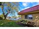 Exterior of home with red roof and lush green lawn with mature shade tree at 9612 Valencia Cv, Bradenton, FL 34210