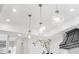 Stylish kitchen with unique lighting fixtures, white cabinets and vent hood at 8030 Midnight Pass Rd, Sarasota, FL 34242