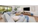 Light-filled living room with sectional sofa, large TV, and wood floors at 8030 Midnight Pass Rd, Sarasota, FL 34242