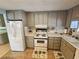 Kitchen with taupe cabinets, white appliances, and tile floor at 5317 Chateau Ln, Bradenton, FL 34207