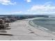 Aerial view of the beach with beachgoers, hotels, condos, and calm ocean water with blue skies and clouds at 5855 Midnight Pass Rd # 319, Sarasota, FL 34242