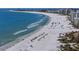An elevated beach view presents many beachgoers relaxing near the water with many blue beach umbrellas lining the shore at 5855 Midnight Pass Rd # 319, Sarasota, FL 34242
