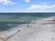 Wide angle aerial view of the shoreline showcasing a beach full of visitors and the tranquil ocean under a blue sky at 5855 Midnight Pass Rd # 319, Sarasota, FL 34242