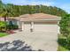 Tan house with three-car garage and landscaped yard at 9115 Kingsbury Pl, Bradenton, FL 34212