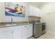 Laundry room with white cabinets, granite countertops, and stainless steel washer and dryer at 3342 Founders Club Dr, Sarasota, FL 34240