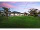 Lovely backyard and lawn at sunset with mature trees, manicured lawn, and screened-in porch at 5819 2Nd Avenue Nw Dr, Bradenton, FL 34209