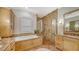 Bright bathroom boasting a standalone tub, glass enclosed shower, and wooden cabinets with granite countertops at 14636 Newtonmore Ln, Lakewood Ranch, FL 34202