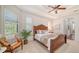 Cozy main bedroom featuring a wooden bed frame, tray ceiling, neutral colors, and natural light from the windows at 14636 Newtonmore Ln, Lakewood Ranch, FL 34202