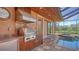 Outdoor kitchen featuring a stainless steel grill, granite countertops, and view of the screened-in pool area at 14636 Newtonmore Ln, Lakewood Ranch, FL 34202