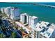 Aerial view of a beachfront condo with parking, palm trees, and a clear blue sky at 226 Golden Gate Pt # 64, Sarasota, FL 34236