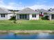 Rear view of single-story home with covered patio, pond view, and lush landscaping at 1119 Waterline Ct, Sarasota, FL 34240