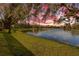 Scenic sunset view over tranquil lake, lush green grass, and mature trees at 12121 Thornhill Ct, Lakewood Ranch, FL 34202
