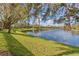 Peaceful lakefront view with green grass and mature trees at 12121 Thornhill Ct, Lakewood Ranch, FL 34202