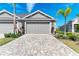 Gray two-car garage with paver driveway, landscaping, and palm trees at 4133 Golden Creek Ter, Parrish, FL 34219