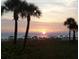 Scenic beach view with palm trees, people enjoying the sunset, and calm ocean waters at 2850 Gulf Of Mexico Dr # 2, Longboat Key, FL 34228
