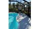 View of clear, screened-in swimming pool with a lounge chair and potted plants on the pool deck at 1594 S Chamberlain Blvd, North Port, FL 34286