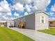 Gray manufactured home with a paved driveway and golf cart at 6421 Kilohee Ct, North Port, FL 34287