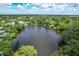 An aerial view showcasing a tranquil lake surrounded by lush greenery and upscale homes at 4431 Camino Real, Sarasota, FL 34231