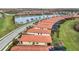 Aerial view of houses with red tile roofs situated along a road, overlooking a lake at 10141 Fiddlewood Dr, Venice, FL 34293