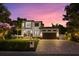 Striking exterior view of a modern home with a large driveway, lush lawn, and vibrant sunset backdrop at 577 Venice Ln, Sarasota, FL 34242