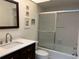 Bathroom featuring a modern vanity, tiled walls, and a bathtub with a glass enclosure at 7234 Cloister Dr # 7234, Sarasota, FL 34231