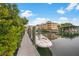 Boat dock with a boat, clear skies, and a view of the building and surrounding lush green landscaping at 14041 Bellagio Way # 214, Osprey, FL 34229