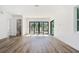 A minimalist living area with light wood flooring and a doorway revealing a bathroom with tiled walls at 2318 Bay St, Sarasota, FL 34237