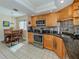 Galley kitchen with granite countertops, light wood cabinets, and stainless steel appliances at 232 Woodland Dr, Osprey, FL 34229