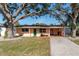 Charming single-story home with a green lawn, mature trees, and a welcoming green front door at 1841 Buccaneer Dr, Sarasota, FL 34231
