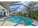 Screened-in pool area featuring a sparkling pool, tropical plants, and ample space for outdoor relaxation at 218 Brandywine Circle, Englewood, FL 34223