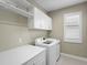 Bright laundry room with white cabinets, washer, and dryer at 7996 Sandstar Way, Sarasota, FL 34240