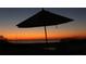 Tranquil beach scene at sunset with a beach umbrella and lounge chair at 5941 Gulf Of Mexico Dr, Longboat Key, FL 34228