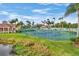 Well-kept tennis courts with players on the court, surrounded by green lawns and palm trees under a clear blue sky at 2921 Seasons Blvd, Sarasota, FL 34240