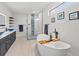 Bathroom featuring large tub, a walk-in shower with glass door, and black vanity with blue glass sink at 6741 Rookery Lake Dr, Bradenton, FL 34212