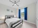 Bright bedroom with a metal upholstered bed frame, ceiling fan, and a window with bright blue curtains at 6741 Rookery Lake Dr, Bradenton, FL 34212