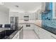 Bright kitchen with stainless appliances, modern white cabinets, black countertops, and a unique backsplash at 6741 Rookery Lake Dr, Bradenton, FL 34212