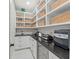 Pantry featuring shelving, white cabinets, black countertops, and appliances at 6741 Rookery Lake Dr, Bradenton, FL 34212